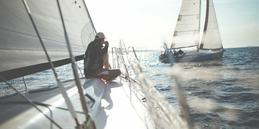 man sits on the deck of a sailboat