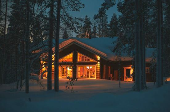 cabin in the forest in the evening with lights in the windows wintertime