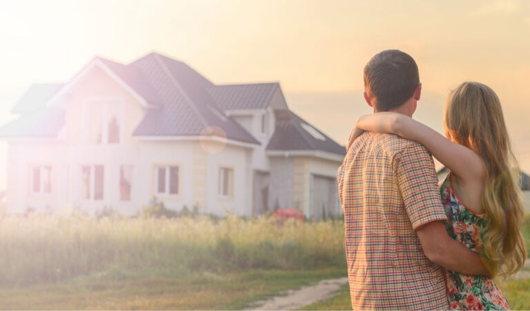 Gutt og jente står med ryggen til og ser på et hus i solnedgang