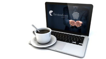 åpen laptop med logoen til eiendomsfinans og en kaffefopp